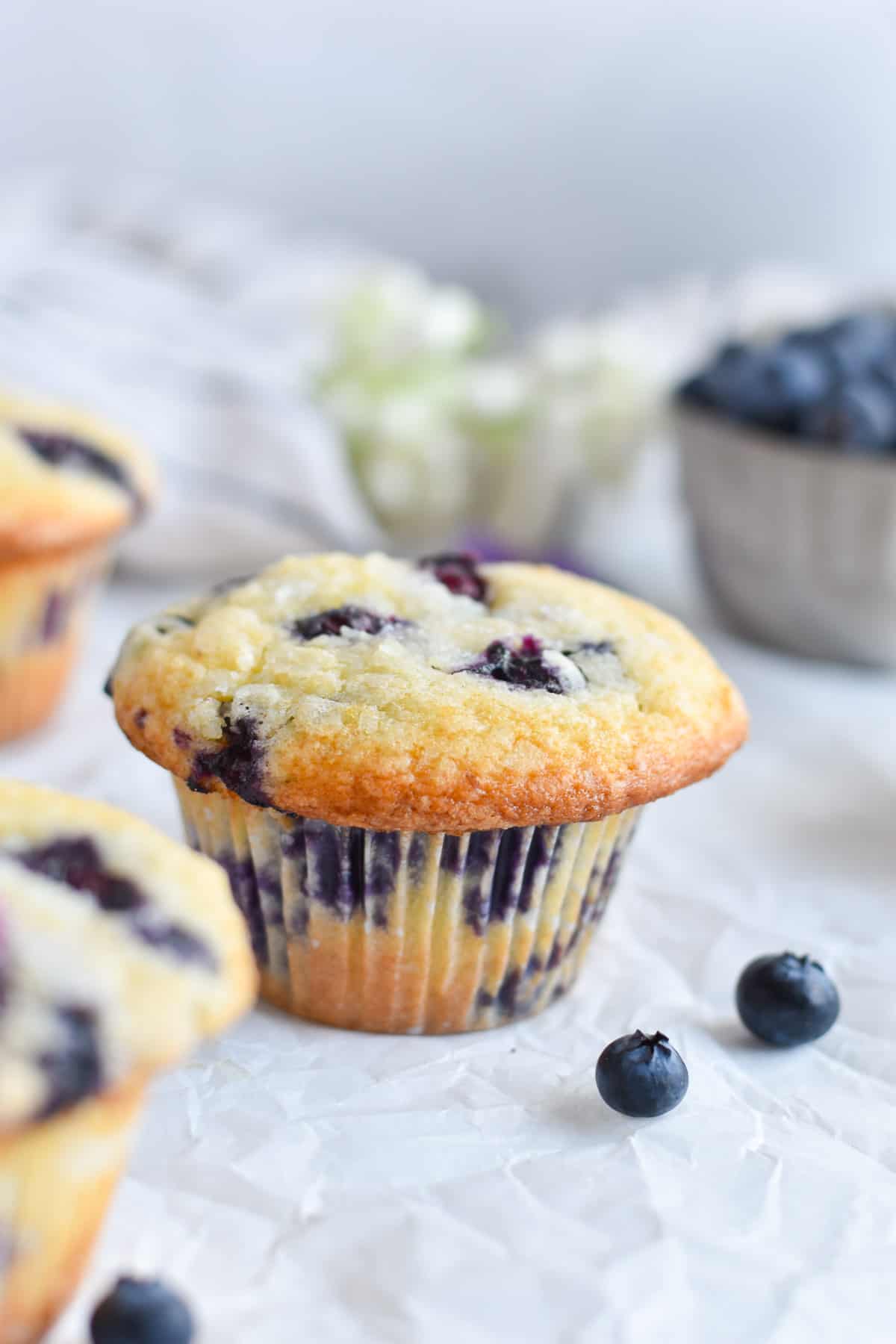 blueberry muffin on white paper with fresh berries around. 