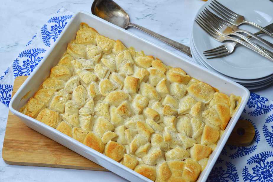 Full pan of biscuits and gravy casserole with blue dish towel and white plates