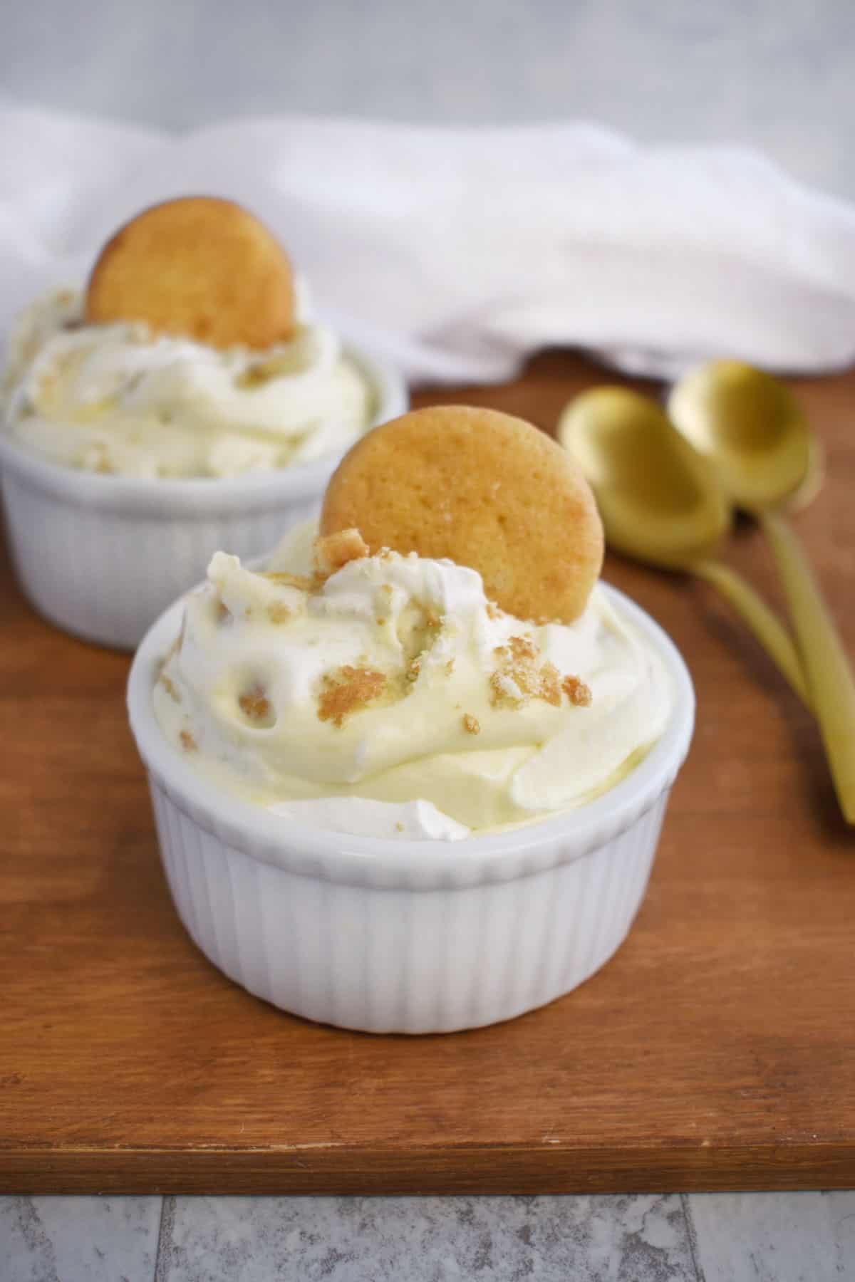 white cup filled with banana pudding topped with a vanilla wafer cookie. 
