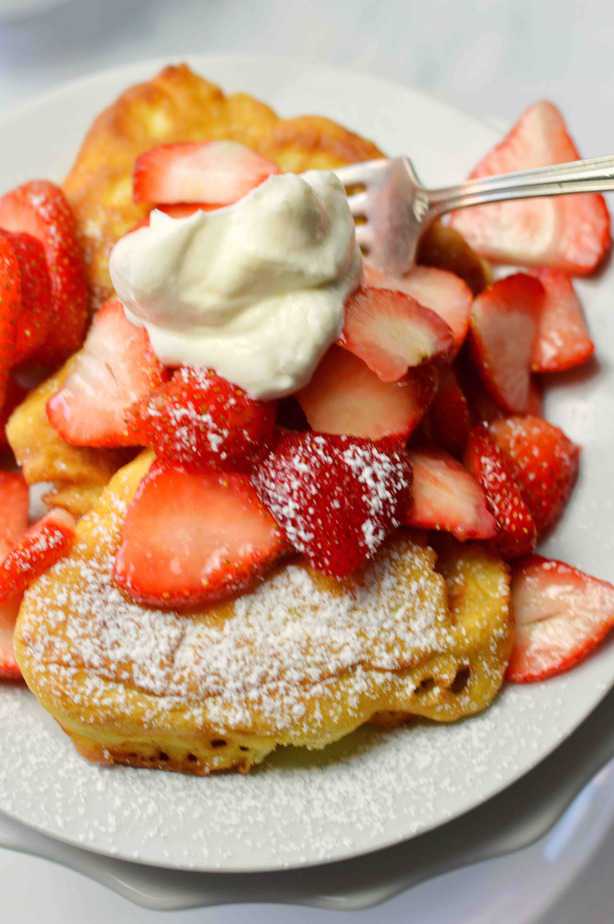 plate of fluffy French toast with strawberries and whipped cream