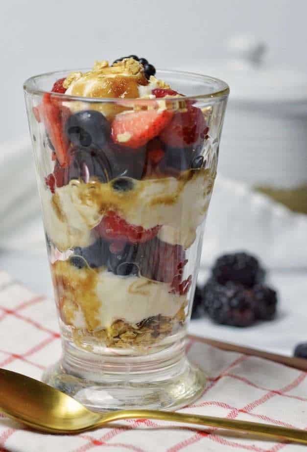 single glass filled with layers of yogurt, berries and granola