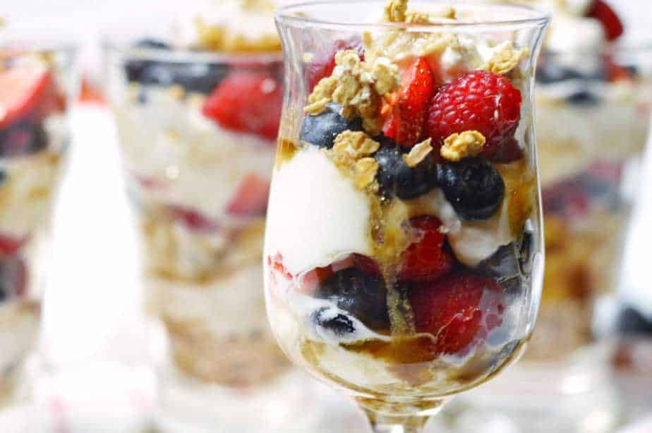 Wine glass filled with layers of yogurt, berries and granola