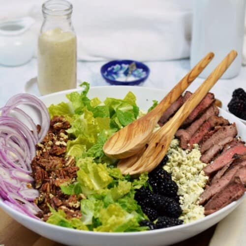 large white bowl with separate ingredients for steak salad and bottle of blue cheese vinaigrette. featured image