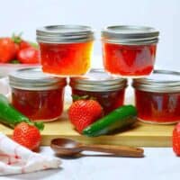 5 jars of jalapeno strawberry jam arranged with fresh strawberries and jalapeños