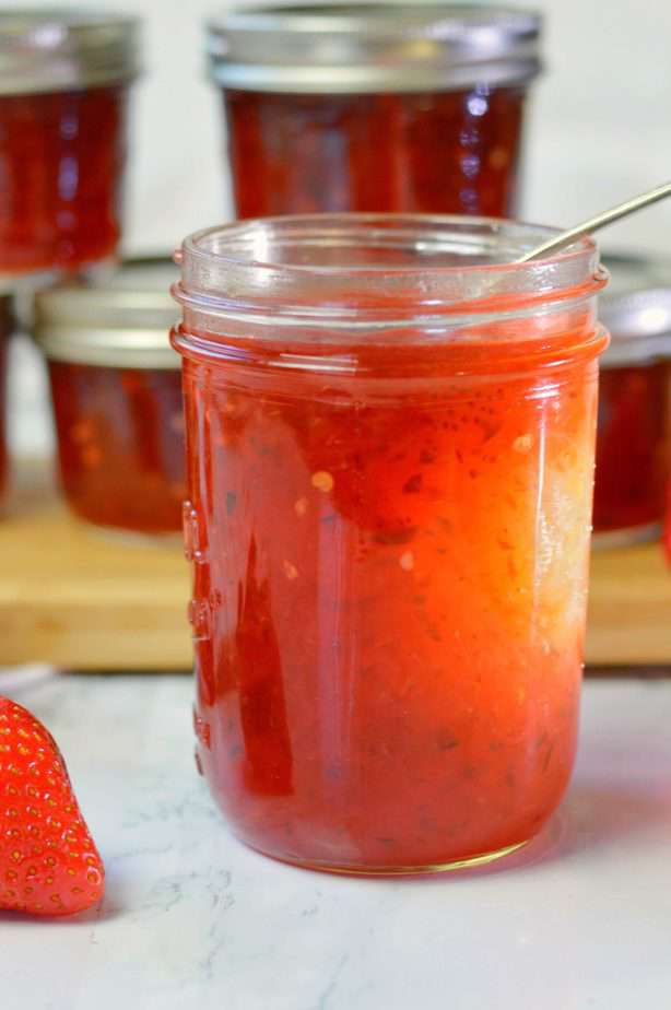 open jar of red jalapeno strawberry jam with spoon