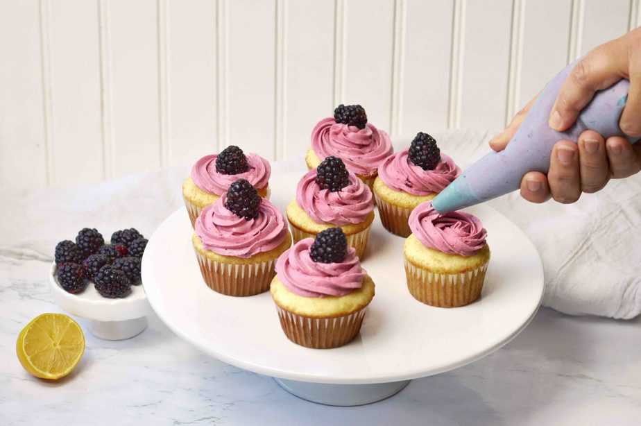 piping bag filled with blackberry buttercream frosting berry cupcakes