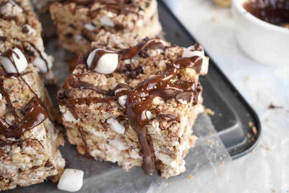 s'more rice krispie treats with chocolate dripping off edge, sitting on edge of cooke sheet