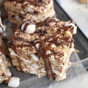 smores rice krispie treat sitting on edge of pan with chocolate dripping off edge