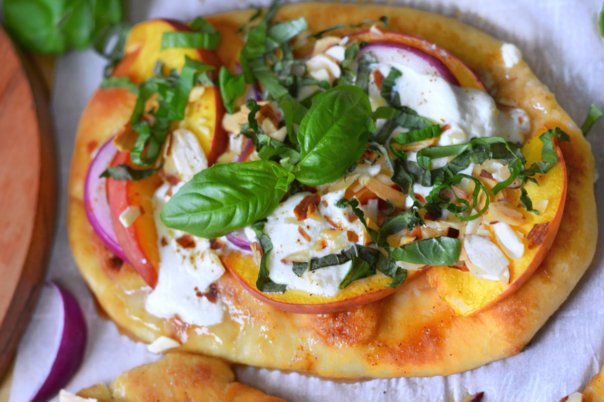 One single burrata and peach pizza topped with burrata cheese, peaches and other ingredients.