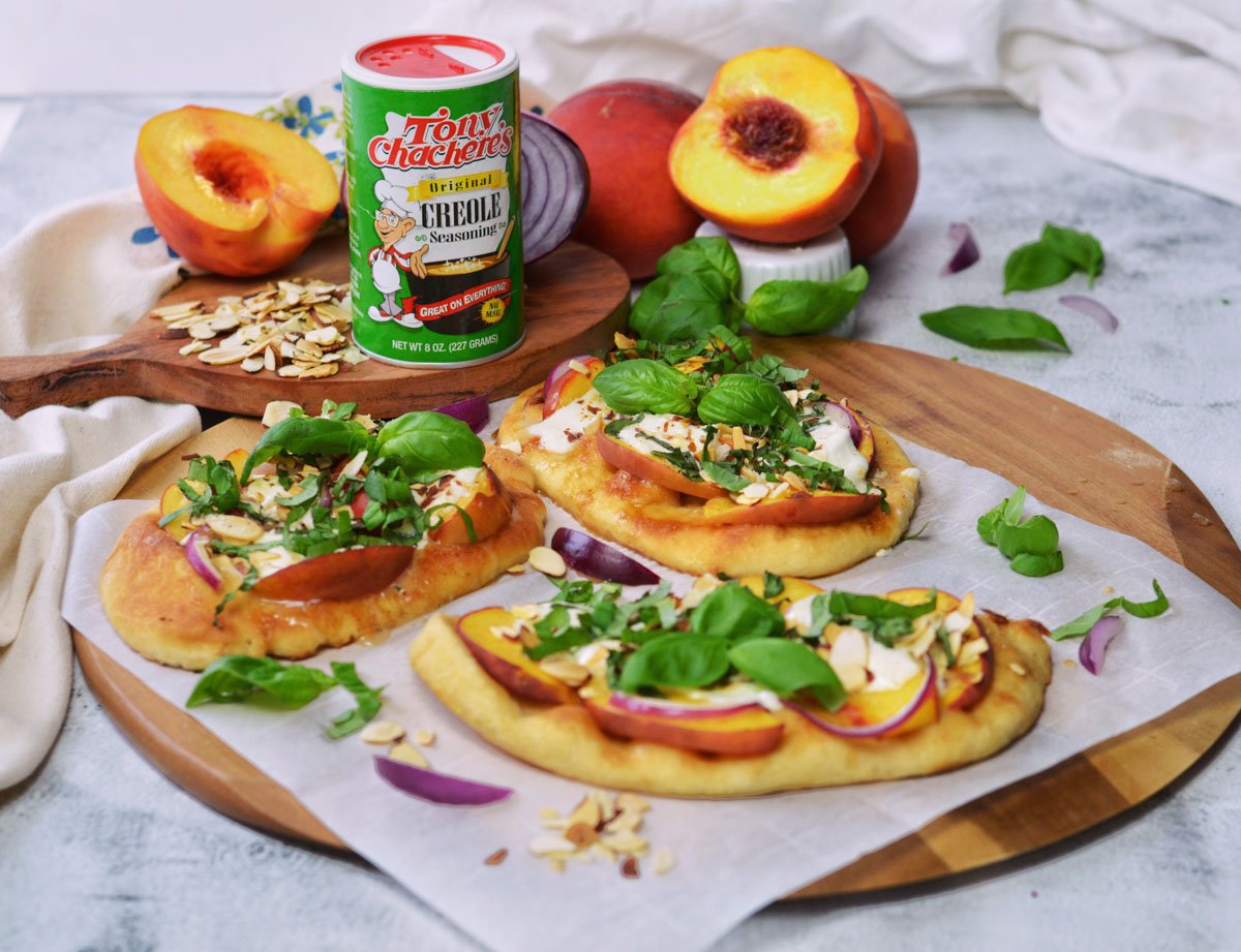 Burrata and peach flat bread pizzas with shaker of Tony Chachere's Original Creole seasoning, and other ingredients.