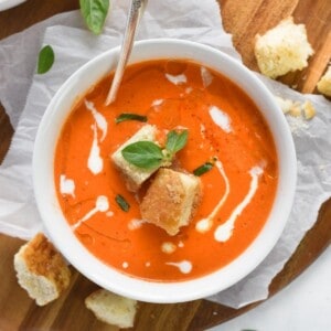 soup in bowl with basil around and croutons on side.