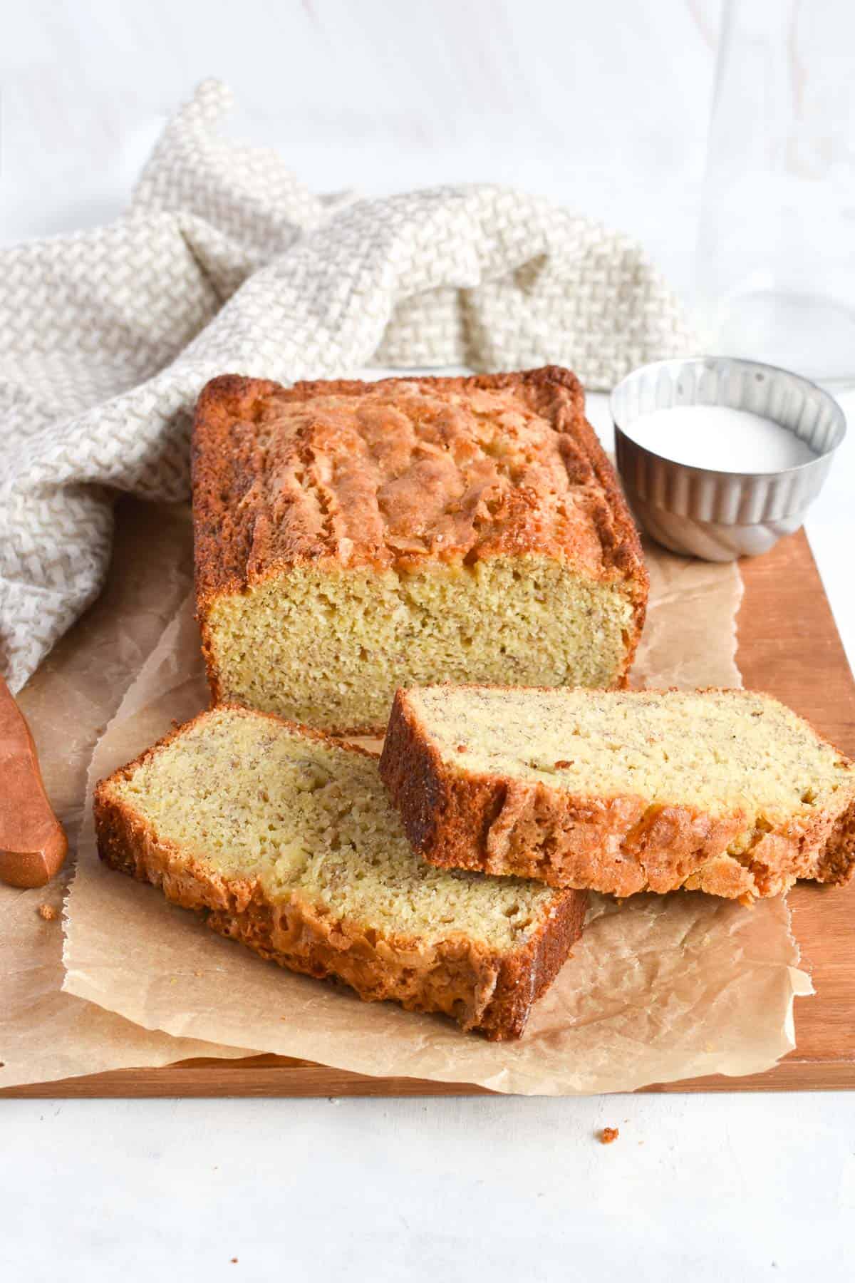 banana bread loaf with two slices of bread in front. 