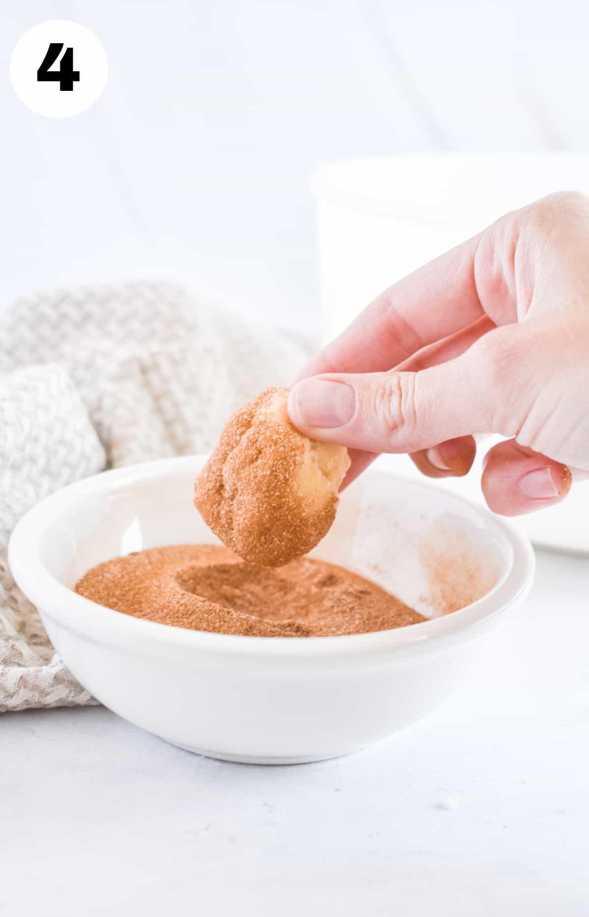 hand holding cookie dough ball rolled in cinnamon sugar. 