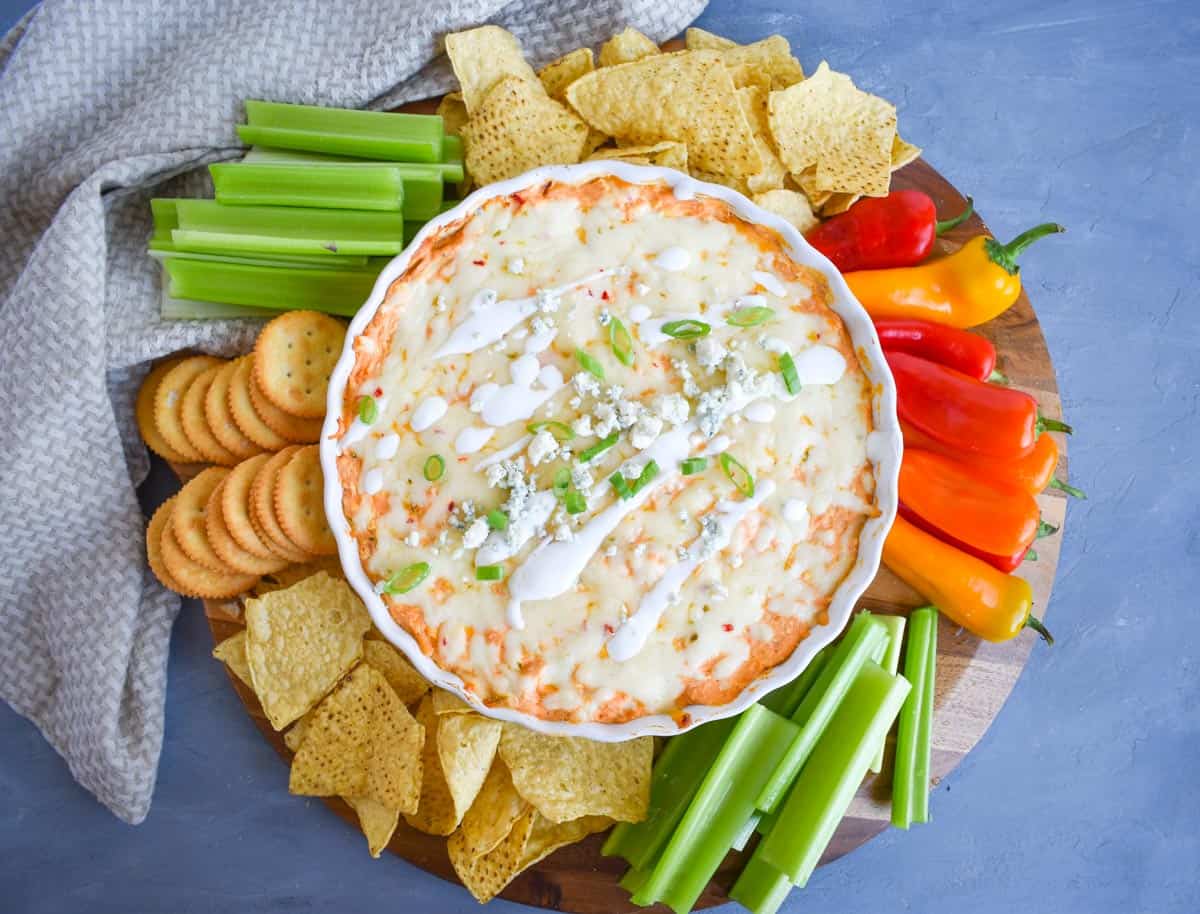 baking dish full of dip surrounded by vegetables and chips. 