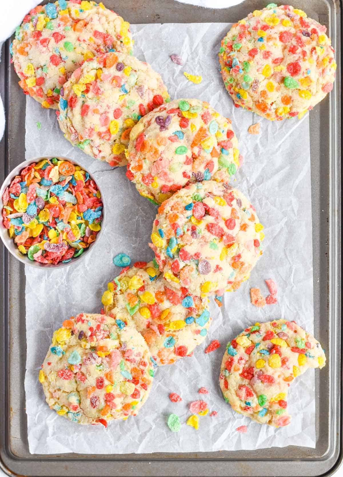 fruity pebbles cookies laid out on top of each other on baking sheet. 