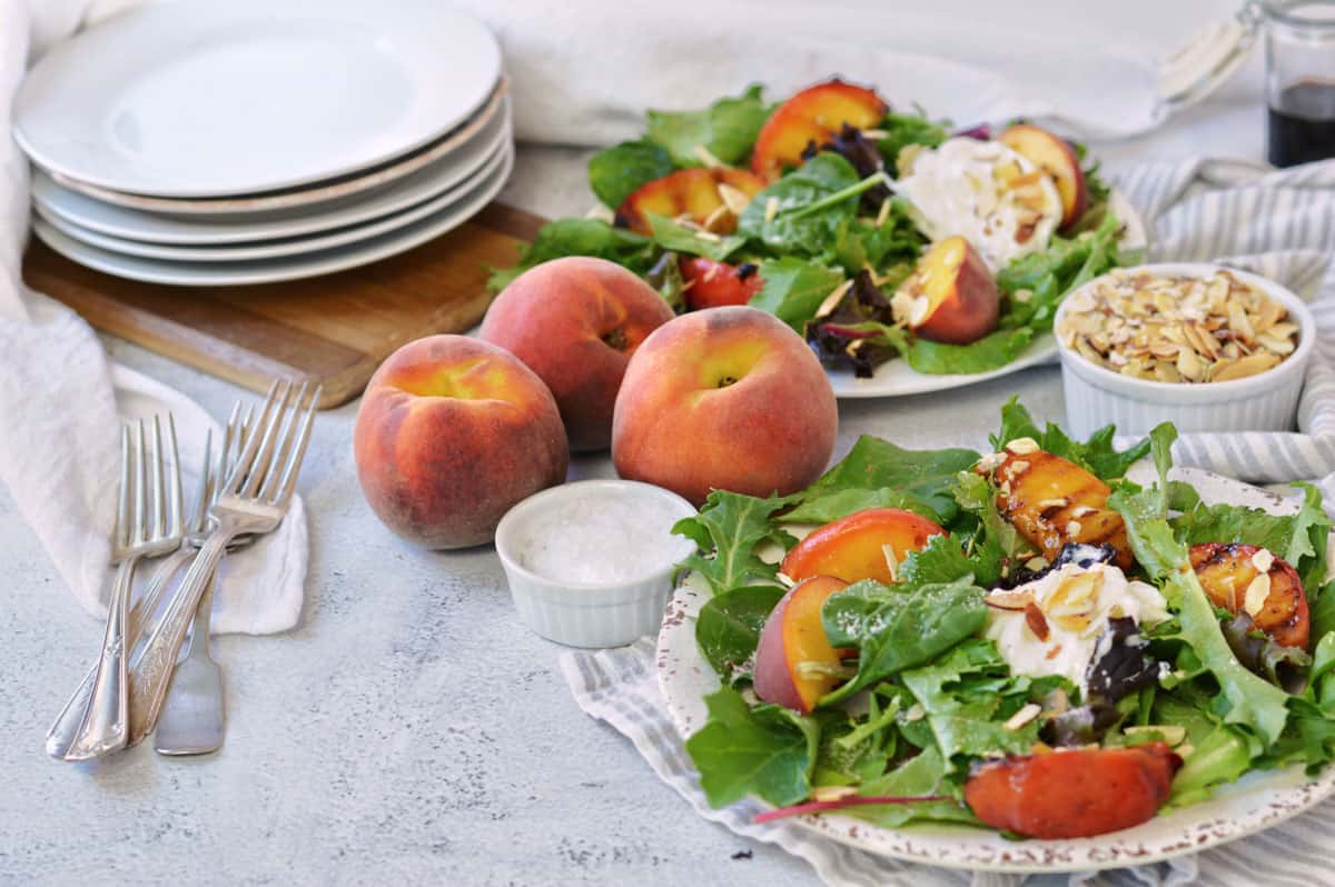 two plates with peaches and burrata salad.