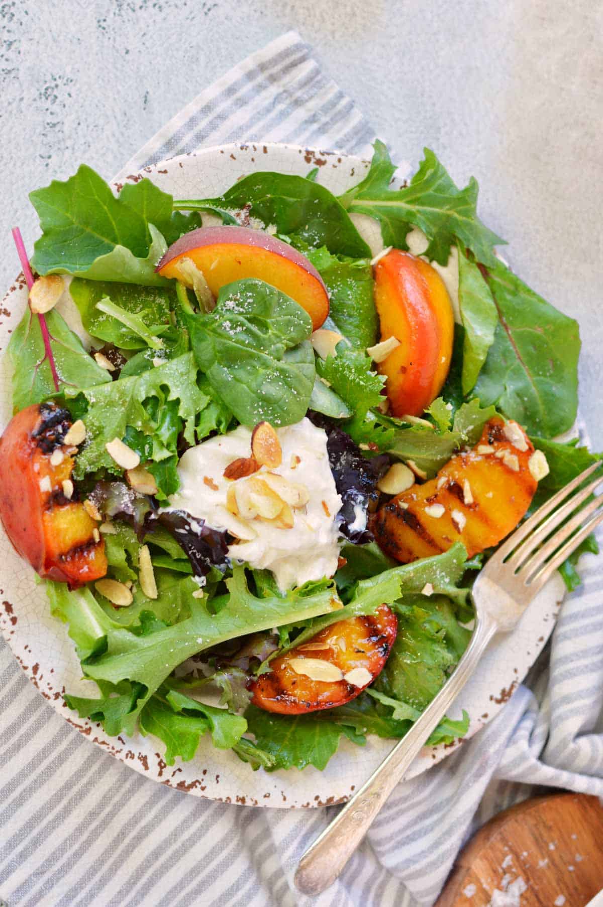 single serving of peach burrata salad with fork.