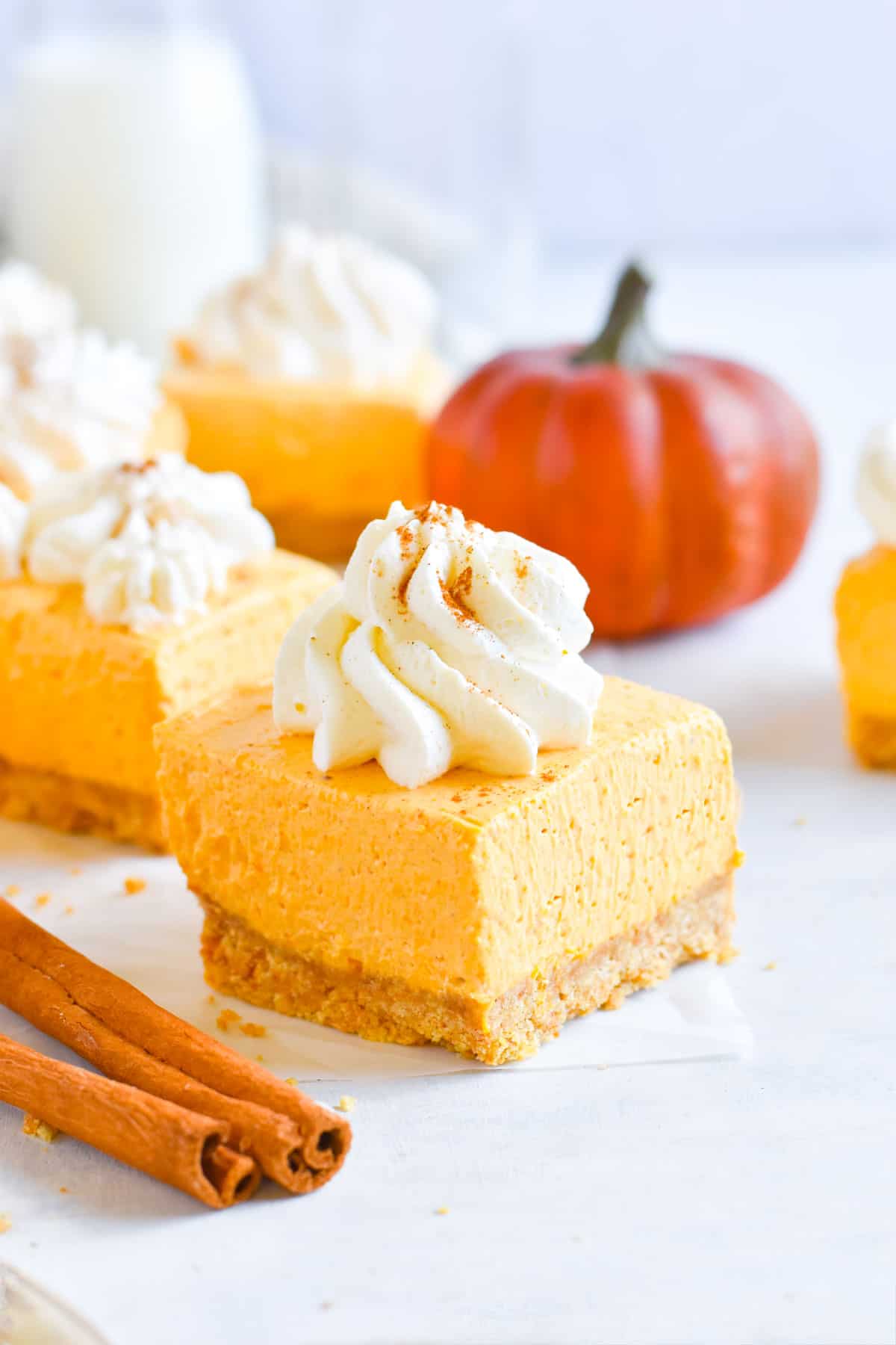 pumpkin cheesecake square with swirl of whipped cream on top. 