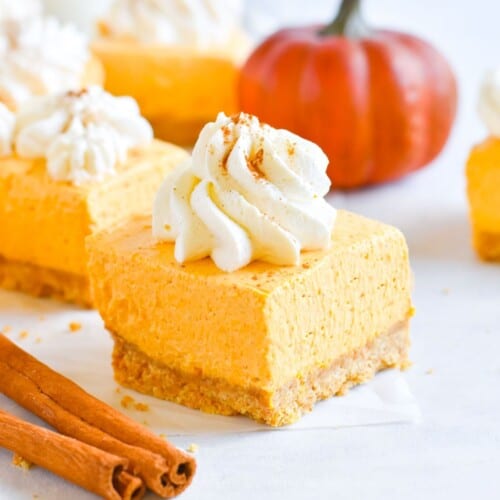 cheesecake square with pumpkin in the background.