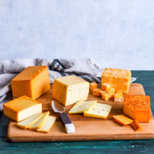 smoked cheese blocks sliced on wooden board.