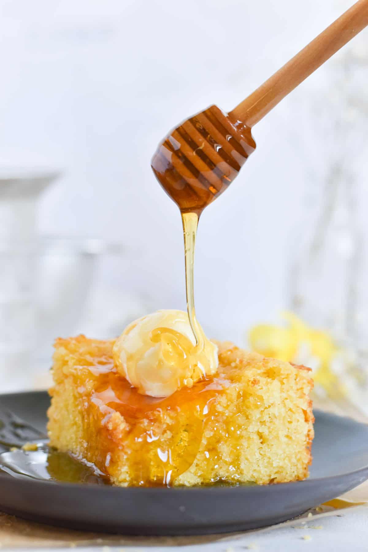 honey being drizzled over a large square of cornbread.