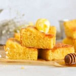 cornbread stacked on top of each other with butter and honey on top.