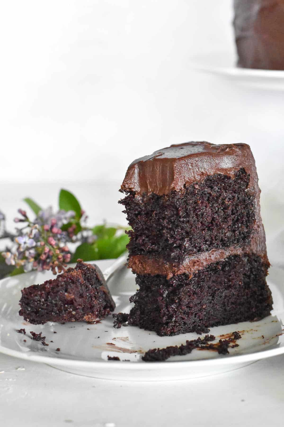 slice of chocolate cake on white plate with bite out of it. 