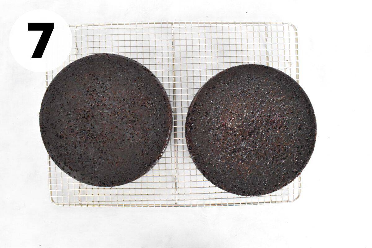 two round chocolate cakes being cooled on cooling rack.