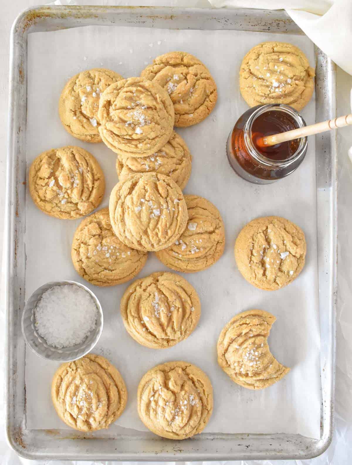 Salted honey cookies with jar of honey on a baking sheet.